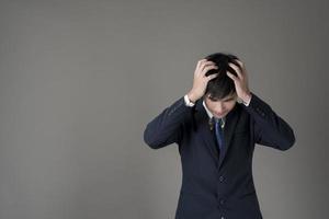 hombre de negocios es dolor de cabeza, fondo gris en estudio foto