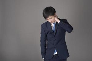 Business man is having neck pain ,grey background in studio photo