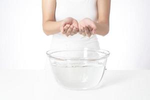 Beautiful woman is washing her face on white background photo