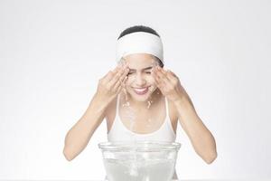 Beautiful woman is washing her face on white background photo