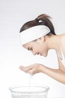 Beautiful woman is washing her face on white background photo