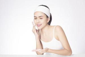 Beautiful woman is washing her face on white background photo