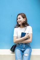 Portrait of beautiful university student is smiling on blue wall background photo