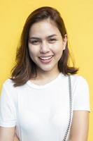 Retrato de hermosa estudiante universitaria están sonriendo sobre fondo de pared amarilla