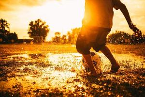 action sport picture of a group of kids playing soccer football for exercise in community rural area under the rain photo