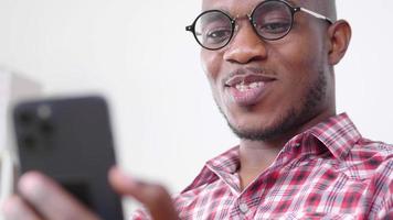 African Man Sitting on Sofa and Using Smartphone video