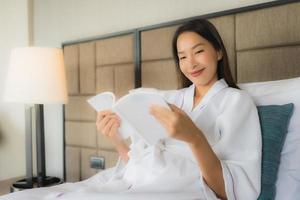 Portrait beautiful young asian women with coffee cup and book on bed photo