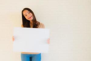 Retrato hermosas mujeres asiáticas jóvenes muestran tablero de papel blanco en blanco foto