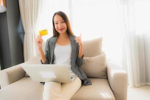 Retrato de hermosas mujeres asiáticas jóvenes usando computadora portátil o teléfono inteligente y móvil con tarjeta de crédito para compras en línea foto