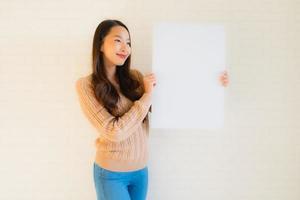 Retrato hermosas mujeres asiáticas jóvenes muestran tablero de papel blanco en blanco foto
