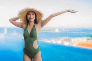 Hermosas mujeres asiáticas jóvenes sonrisa feliz relajarse alrededor de la piscina al aire libre en el hotel resort para viajar en vacaciones foto