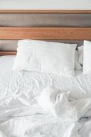White pillow with rumpled bed photo