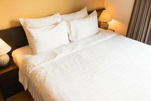 White comfortable pillow on bed with light lamp photo