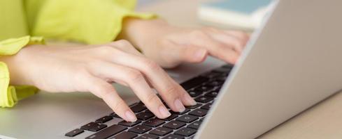 Closeup of hand young asian businesswoman working on laptop computer on desk at home office, freelance looking and typing on notebook on table, woman studying online, business and education concept. photo