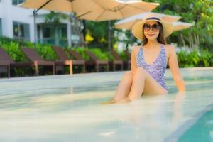 Hermosas mujeres asiáticas jóvenes sonrisa feliz relajarse alrededor de la piscina al aire libre en el hotel resort para viajar en vacaciones foto