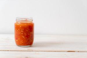 Chili or chili sauce in bottle and jar on wood background photo