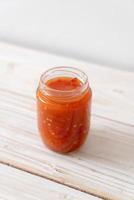 Chili or chili sauce in bottle and jar on wood background photo