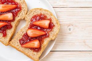 pan integral casero con mermelada de fresa y fresa fresca foto