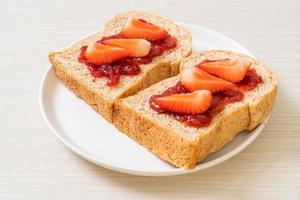 pan integral casero con mermelada de fresa y fresa fresca foto