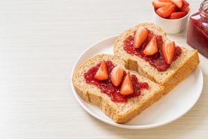 pan integral casero con mermelada de fresa y fresa fresca foto