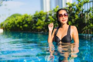 Retrato hermosas mujeres asiáticas jóvenes sonrisa feliz relajarse piscina al aire libre en el resort foto