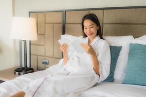 Portrait beautiful young asian women with coffee cup and book on bed photo