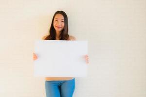 Retrato hermosas mujeres asiáticas jóvenes muestran tablero de papel blanco en blanco foto