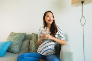 Portrait beautiful young asian women holding drink water glass on sofa photo