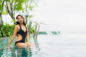 Retrato hermosas mujeres asiáticas jóvenes sonrisa feliz relajarse piscina al aire libre en el resort foto