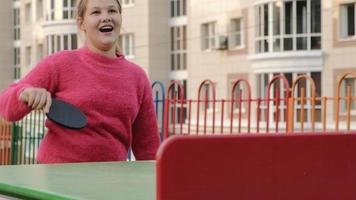 Jovencita jugando tenis de mesa al aire libre