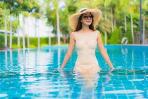 Retrato hermosas mujeres asiáticas jóvenes sonrisa feliz relajarse piscina al aire libre en el resort foto