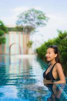 Retrato hermosas mujeres asiáticas jóvenes sonrisa feliz relajarse piscina al aire libre en el resort foto