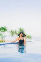 retrato, hermoso, joven, mujeres asiáticas, feliz, sonrisa, relajarse, piscina al aire libre, en, hotel foto