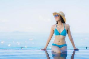Retrato hermosas mujeres asiáticas jóvenes sonrisa feliz relajarse piscina al aire libre en el resort