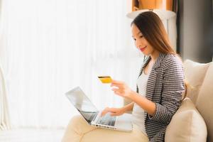 Retrato de hermosas mujeres asiáticas jóvenes usando computadora portátil o teléfono inteligente y móvil con tarjeta de crédito para compras en línea foto