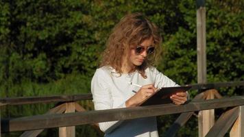 Woman is using a computer tablet outdoors