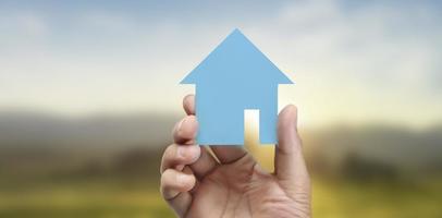 Hands holding  paper house, family home protecting insurance concept photo