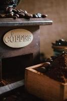 Bodegón con granos de café y antiguo molino de café en el fondo rústico foto