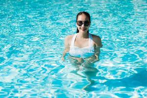 Hermosa joven asiática feliz y sonrisa en la piscina para relajarse viajes y vacaciones foto