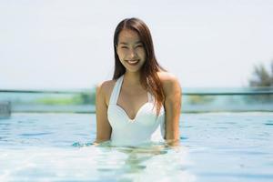 Hermosa joven asiática feliz y sonrisa en la piscina para relajarse viajes y vacaciones foto