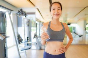 Portrait beautiful young asian woman with bottle water in gym photo