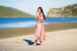 Portrait young beautiful asian woman walk smile and happy on the beach sea and ocean photo