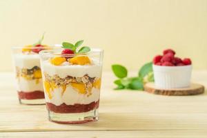 mango fresco casero y frambuesa fresca con yogur y granola - estilo de comida saludable foto