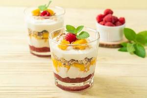 mango fresco casero y frambuesa fresca con yogur y granola - estilo de comida saludable foto