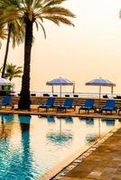 Hermosa palmera con sombrilla piscina en hotel resort de lujo al amanecer - concepto de vacaciones y vacaciones