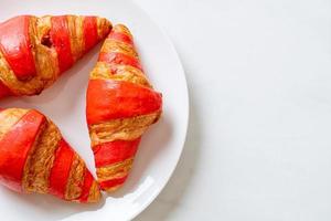 Fresh croissant with strawberry jam sauce on plate photo