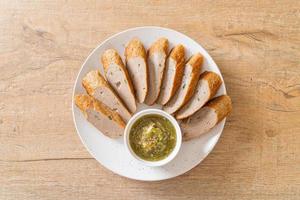 Fried Chinese fish cake or fish ball line sliced with spicy seafood dipping sauce photo