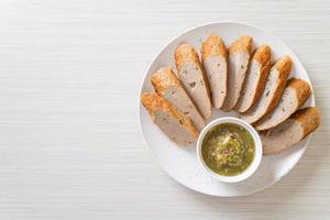 Fried Chinese fish cake or fish ball line sliced with spicy seafood dipping sauce photo