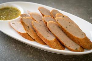 Fried Chinese fish cake or fish ball line sliced with spicy seafood dipping sauce photo