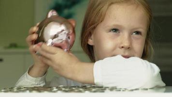 Girl puts money in a pink piggy bank video